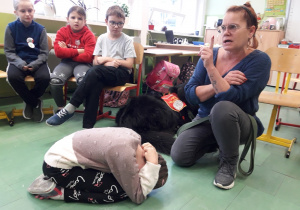 Opiekunka psa instruuje grupę uczniów, jak bezpiecznie zachowywać się wobec psa.