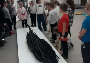 Grupa uczniów słucha informacji na temat wybranych dzieł z kolekcji galerii.