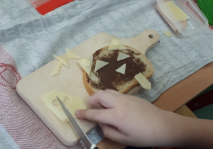 Dziecko kroi składniki na kanapkę.