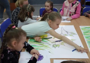 Przedszkolaki kolorują wspólnie motywy z baśni Hansa Christiana Andersena "Słowik" i "Stokrotka" oraz przyklejają je na plakaty "Baśniowa szkoła"