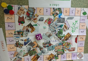 Gra planszowa "Segregujemy odpady" z pionkami i kostka do gry oraz karty wykonana przez uczniów klasy 4a