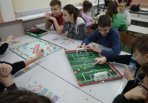 Grupa uczniów grająca w „Monopoly” i piłkarzyki.