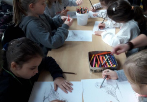 Grupa uczniów koloruje ilustrację wróbla